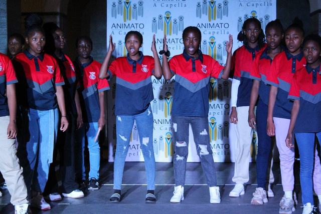 Learners in red and navy shirts posing in front of a banner